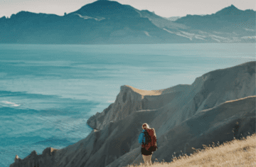 person standing on cliff overlooking mountains cinematic