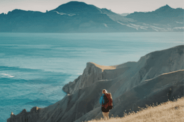 person standing on cliff overlooking mountains cinematic