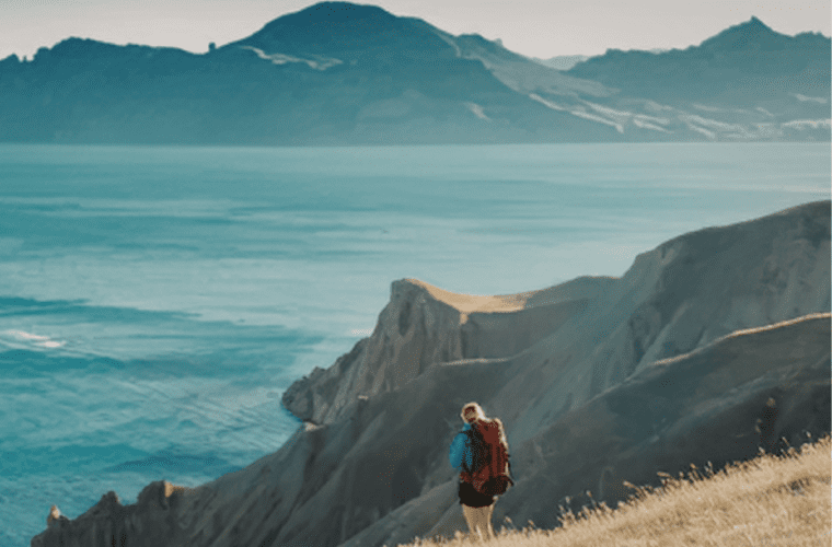 person standing on cliff overlooking mountains cinematic
